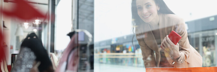 Smiling woman looks at shop window with women shoes