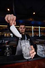 Barman puts the ice cubes into a glass