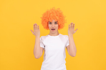 surprised freaky woman in curly clown wig with raised hands, surprise