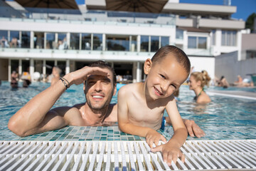 Father and son, happy, smiling, enjoying in the swimming pool