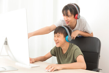 Two multiethnic teenage boys with headphone have fun with computer games at home.