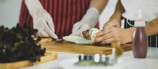 Obraz premium Unrecognized boy cutting fresh onion near woman while cooking lunch together in contemporary light kitchen in weekend at home. Concept for education and learning by doing of modern kid