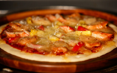Background, Selective focus and close up on tasty homemade seafood pizza with shrimp, pineapples, crab sticks on wooden tray. Food Concept.