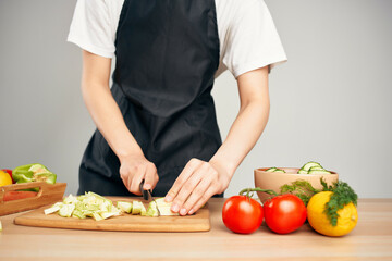 Woman in black apron cutting vegetables housework cooking