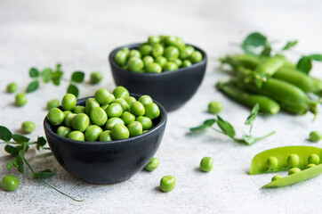 Fresh green peas pods and green peas with sprouts on concrete background.