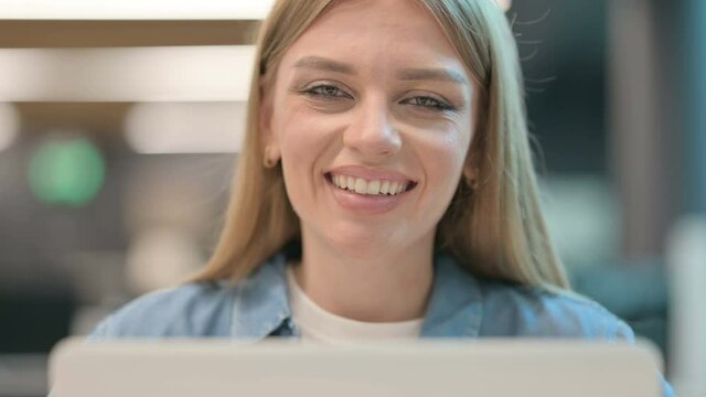 Close Up of Woman Smiling at Camera while using Laptop