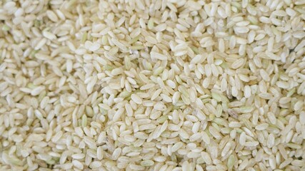 Organic brown rice in a spinning texture, top shot. Close up of traditional asian grains. Eco product for cooking healthy food. Raw ingredient for rice dishes rotating in a macro footage, slow motion.