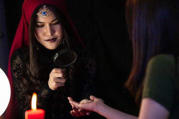 Asian witch examining hand of client