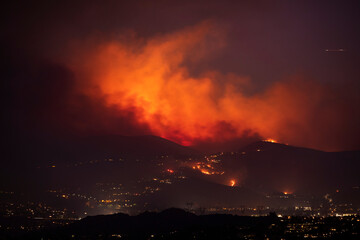 A nighttime wildfire tears through the hills of California.