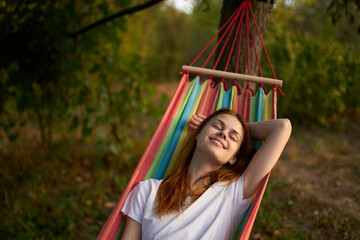 pretty woman with closed eyes outdoors lies in a hammock nature