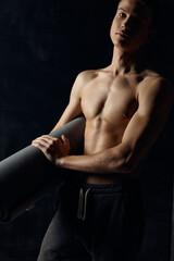 Fototapeta na wymiar athlete in pants nude torso fitness mat black background
