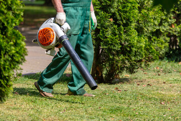 A worker blows dust off the grass