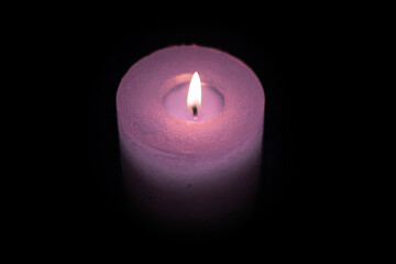 Candle burning in darkness, color purple