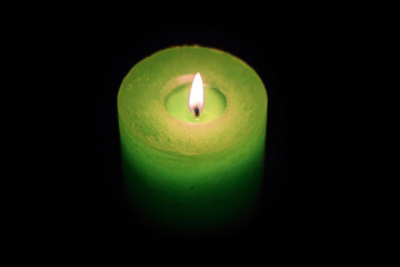 Candle burning in darkness, color green