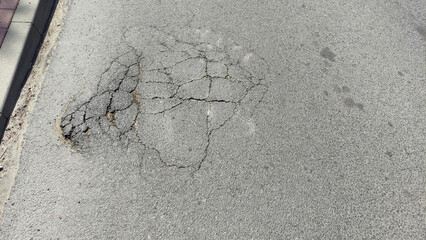 Stara, zniszczona nawierzchnia asfaltowa.