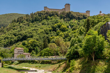 The pedestrian bridge over the dry Tessino stream with the Albornoziana fortress overlooking the hill of Spoleto, Italy