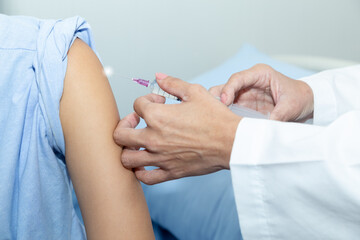 Doctor giving patient vaccine, COVID-19, flu or influenza shot. Vaccination and prevention against flu, Covid-19 virus pandemic with syringe at hospital room.