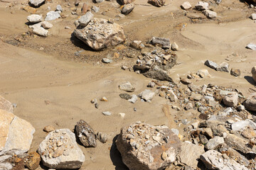 Boulders, pebbles and wet sand of the dry river