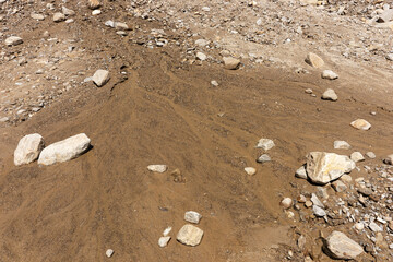 Boulders, pebbles and wet sand of the dry river