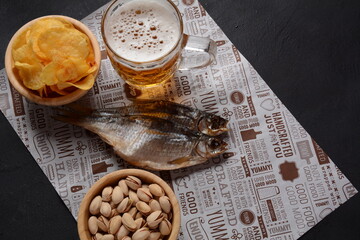 Salty dried fish roach and Beer mug with light foamed beer. Dried roach for beer on craft paper lie...