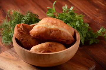 Russian Patties (Pasties, Hot Cakes, Pirozhki, Pies) on wooden cupboard . Traditional homemade fried pies  with potatoes