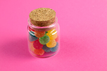 Jar full of rainbow and colorful candies against bright red background