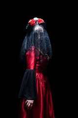 Ghost bride or witch in black veil, red dress and crown with skull and roses on black background. Halloween concept.