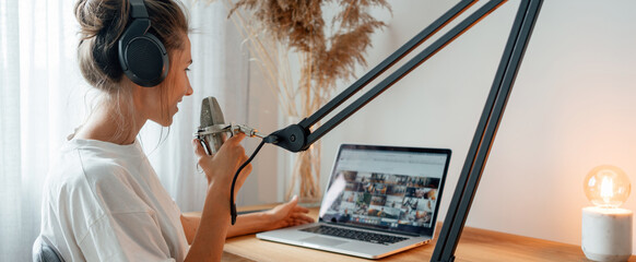 Woman podcaster streaming and broadcasting her podcast from homemade studio. Female recording...