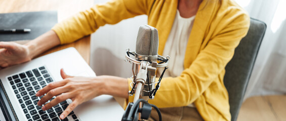 Woman podcaster streaming and broadcasting her podcast from homemade studio. Female recording...