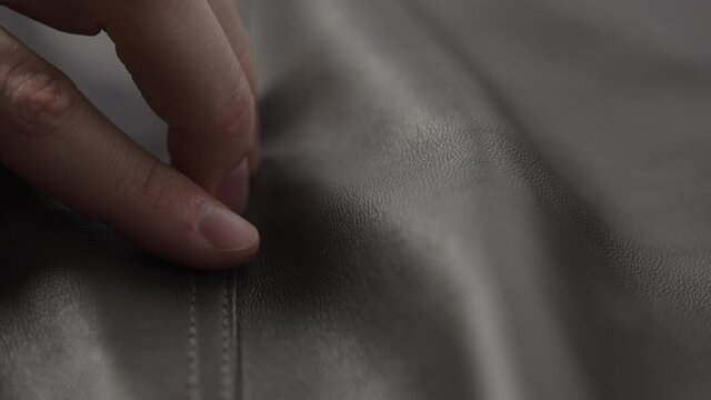 Slide shot man touching fine leather seam closeup