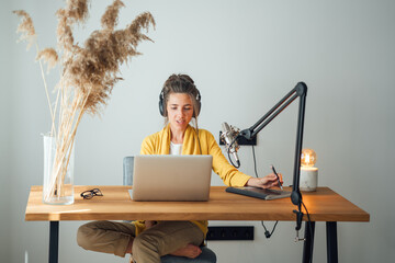 Woman radio host recording podcast at home studio. Female podcaster recording broadcasting into...