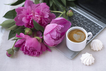 laptop, bouquet of bright pink peonies, cup of coffee, meringue.beautiful romantic still life with flowers. a gift to a colleague