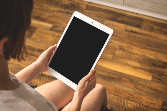 Mockup image with girl in apartment and tablet pc in the hand, wooden background photo with copy space