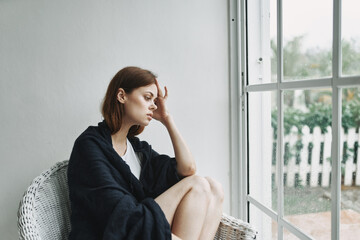 sad woman sitting near the window loneliness pleasure