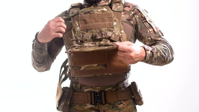 Special Forces soldier in a cartoon camouflage takes a picture plate carrier on a white background
