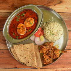 Chicken Thali from an indian cuisine, food platter consists Chicken fry,Boiled egg curry, lentils, jeera rice, and onions. selective