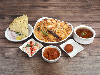 Paneer Biryani Thali - Basmati rice cooked with Cottage cheese, veggies and spices and served with mirchi ka salan,raita,sweet and papad. selective focus