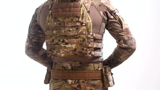 Special operations officer in multicam camouflage and plate carrier puts on a war belt with pouches and rotates 360 degrees against a white background