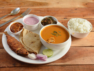 Indian Fish thali from an indian cuisine, consists of fish fry,fish curry, steamed rice, roti and pickle.. selective focus
