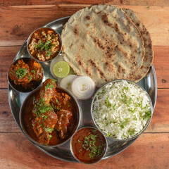 Chicken Thali from an indian cuisine, food platter consists of Chicken curry, lentils, jeera rice, curd and onions., selective focus