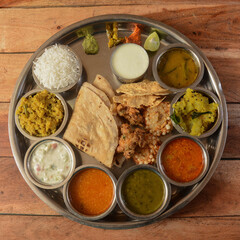 Veg Thali from an indian cuisine, food platter consists variety of veggies,paneer dish, lentils, steamed rice,roti, sweet dish, onion and snack etc., selective focus