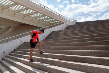 Hispanic sporty guy getting tired in front of stairs and blue sky with clouds