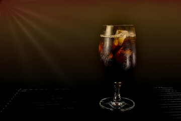 Cola glass with ice cubes on dark background.