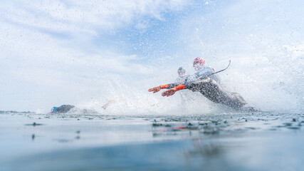 Triathletes in wetsuits jump into the water during a triathlon competition