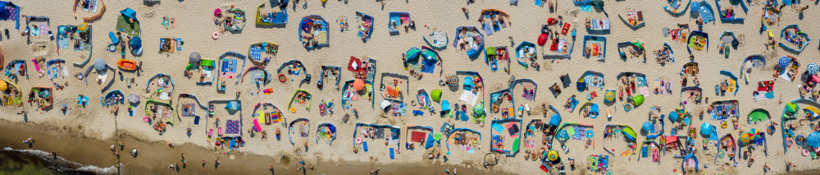 People taking sunbath at Baltic Sea on crowdy, sandy beach in Sarbinowo, Poland