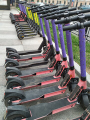 Electric scooters parked in a row on a city street are rented out. 