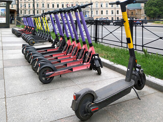Electric scooters parked in a row on a city street are rented out. Ecological transport for...