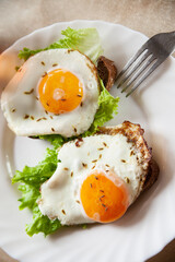 Closeup yummy toasts with fried eggs and lettuce leaves for breakfast placed on wooden board