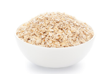 Close-up of dry organic whole rolled oats (Avena sativa)  in a white ceramic bowl over white background