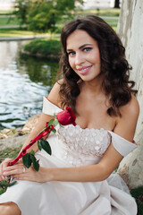 Fototapeta na wymiar Young beautiful lady with red rose in white dress
